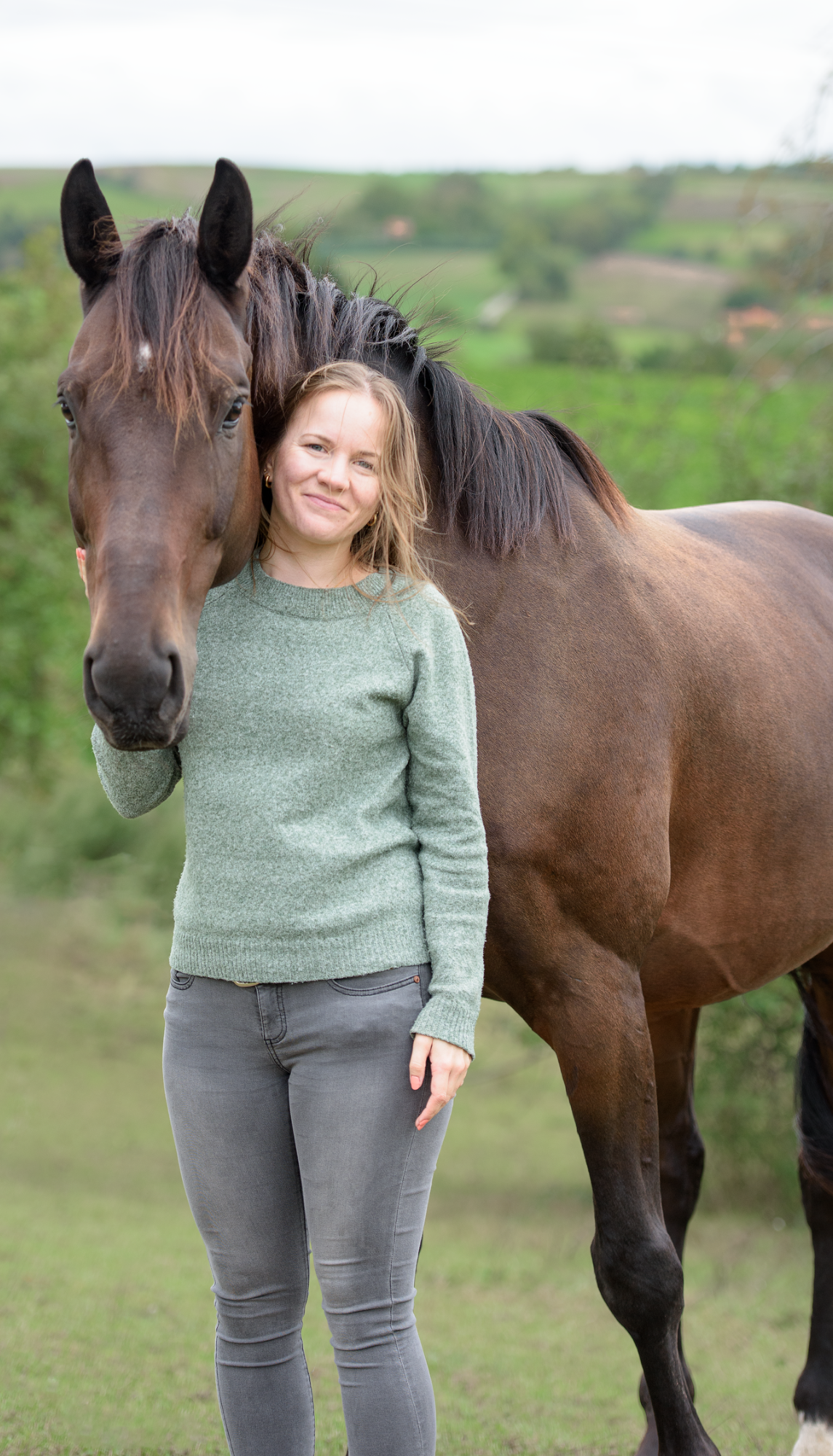 Celine Kalthof mit ihrem Pferd Celine Kalthof steht neben ihrem braunen Pferd und hat ihre Hand an seinem Kopf